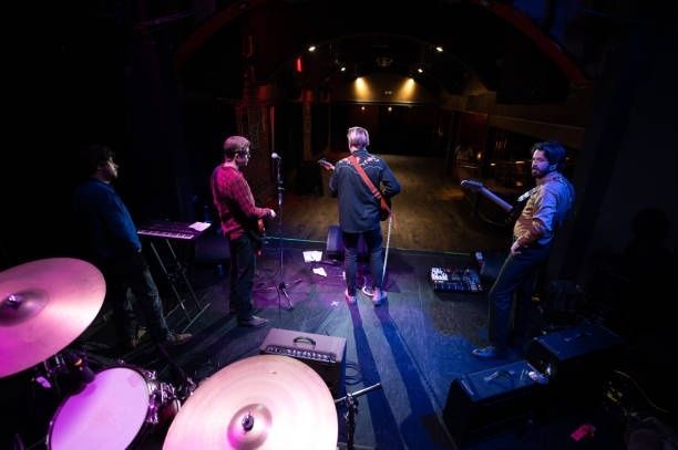 Muzikanten tijdens een soundcheck op een donker podium in een lege zaal